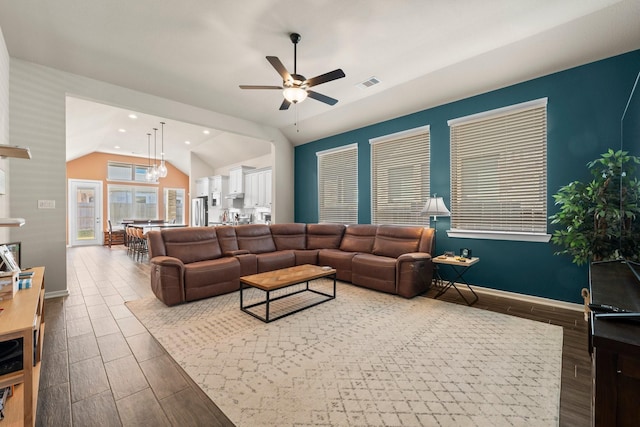 living area with a ceiling fan, baseboards, visible vents, wood finish floors, and lofted ceiling