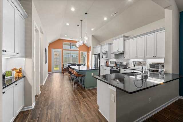 kitchen featuring visible vents, a sink, stainless steel appliances, a breakfast bar area, and wood tiled floor