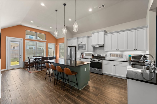 kitchen featuring visible vents, a sink, stainless steel appliances, under cabinet range hood, and dark countertops