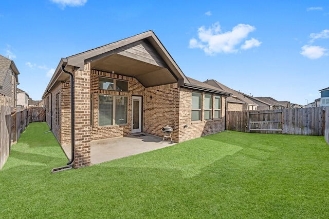 back of house featuring brick siding, a patio area, a lawn, and a fenced backyard