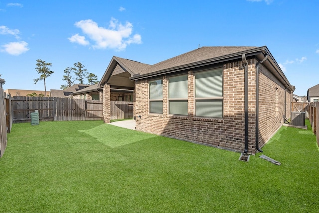 back of house featuring brick siding, a yard, and a fenced backyard