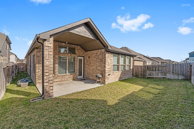 back of house with a yard, brick siding, a fenced backyard, and a patio area