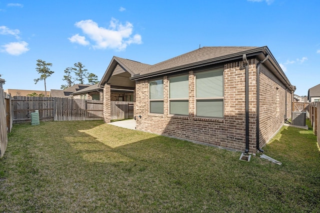 back of property featuring brick siding, a lawn, cooling unit, and a fenced backyard