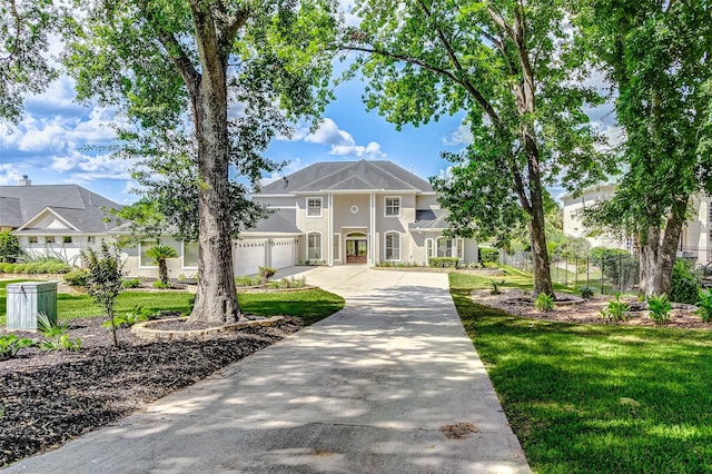 view of front of home featuring stucco siding, concrete driveway, a front yard, and fence