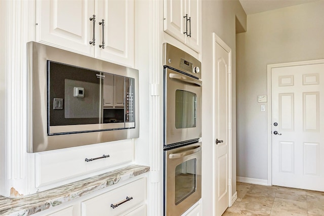 18752 Palm Beach Blvd, Montgomery, TX 77356 - kitchen featuring built in microwave, double oven, white cabinetry, baseboards, and light stone countertops