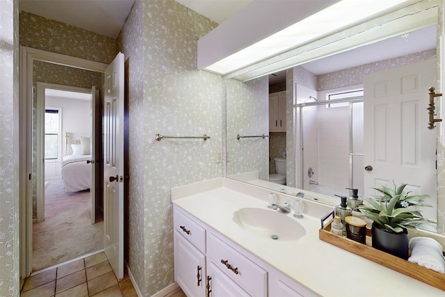 ensuite bathroom with vanity, wallpapered walls, an enclosed shower, tile patterned floors, and toilet