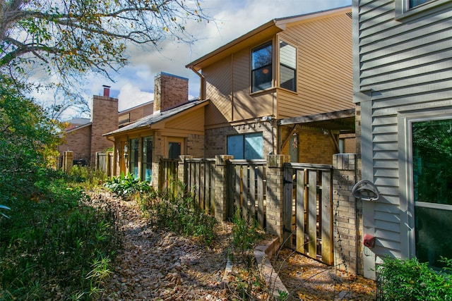 view of side of home featuring brick siding and fence