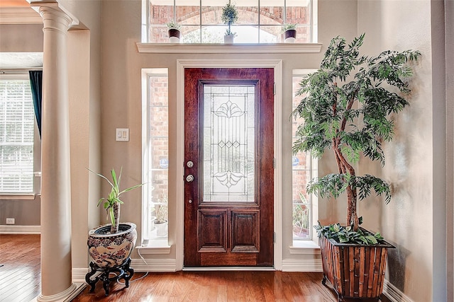 entryway featuring wood finished floors, baseboards, and decorative columns