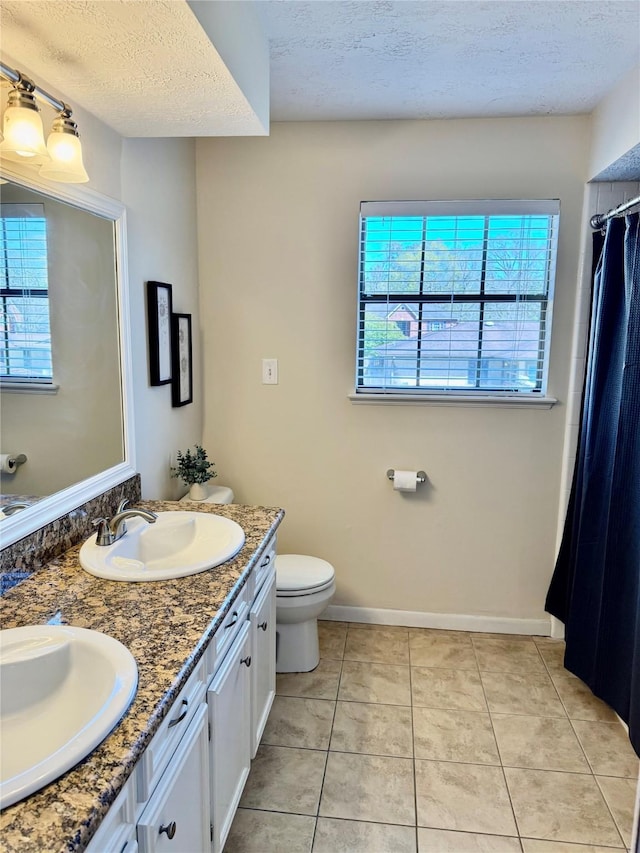 full bathroom featuring tile patterned flooring, a textured ceiling, toilet, and a sink