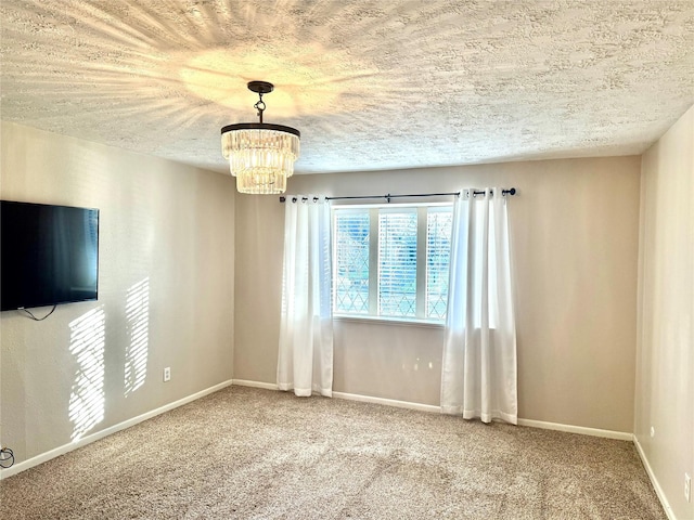 carpeted spare room with a notable chandelier, baseboards, and a textured ceiling