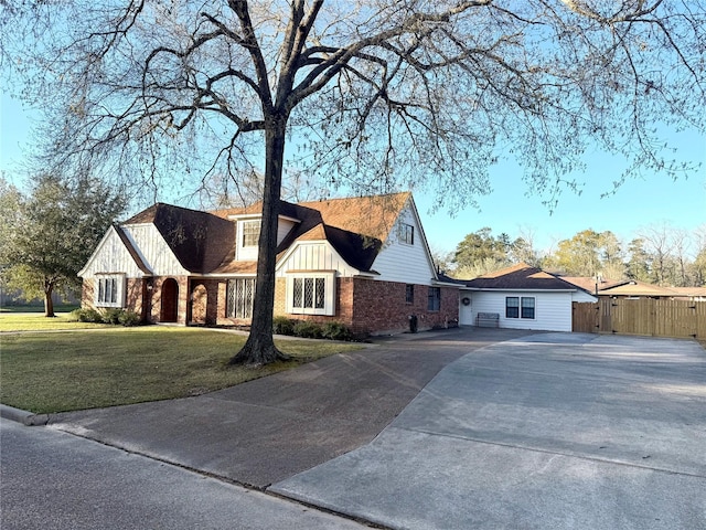 view of front of house featuring a front lawn, aphalt driveway, fence, board and batten siding, and brick siding