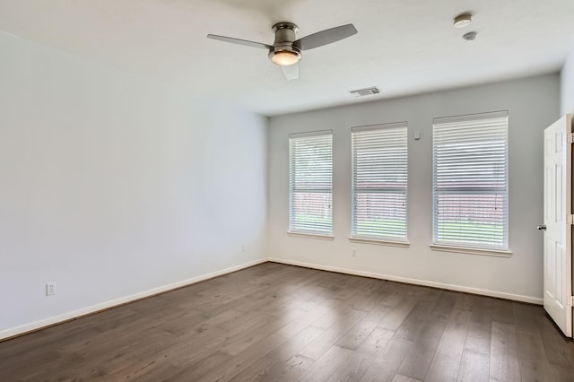 spare room featuring visible vents, baseboards, and dark wood-style floors