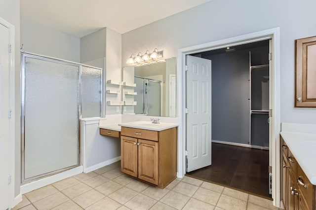 full bath with tile patterned floors, a stall shower, vanity, and baseboards