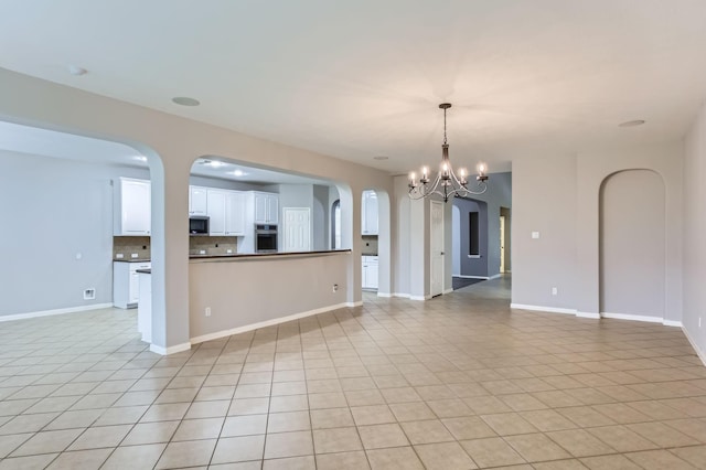 unfurnished living room featuring light tile patterned floors, arched walkways, baseboards, and a chandelier