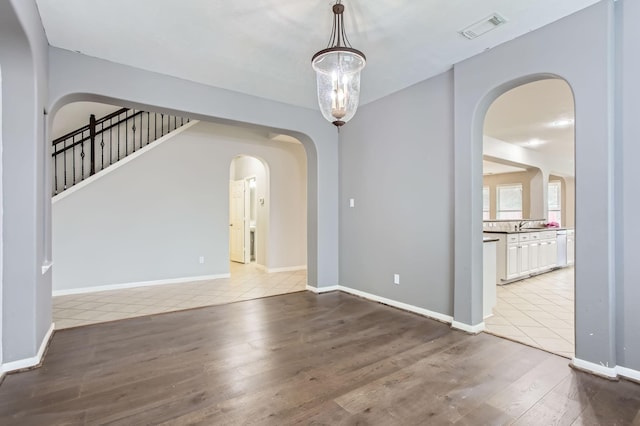 interior space featuring arched walkways, visible vents, baseboards, and wood finished floors