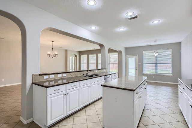 kitchen with light tile patterned floors, visible vents, a kitchen island, a sink, and dishwasher