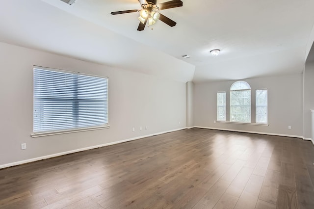 empty room featuring lofted ceiling, baseboards, and dark wood-type flooring