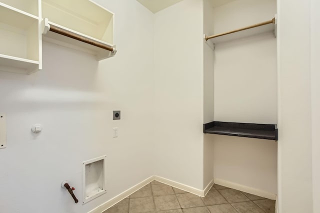 laundry area with baseboards, gas dryer hookup, light tile patterned floors, laundry area, and hookup for an electric dryer