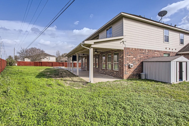 back of property featuring brick siding, ceiling fan, a fenced backyard, a patio area, and a storage unit