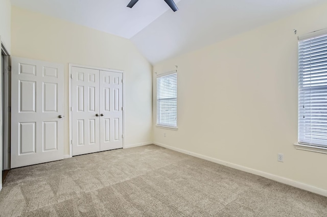 unfurnished bedroom with baseboards, carpet, vaulted ceiling, a closet, and a ceiling fan