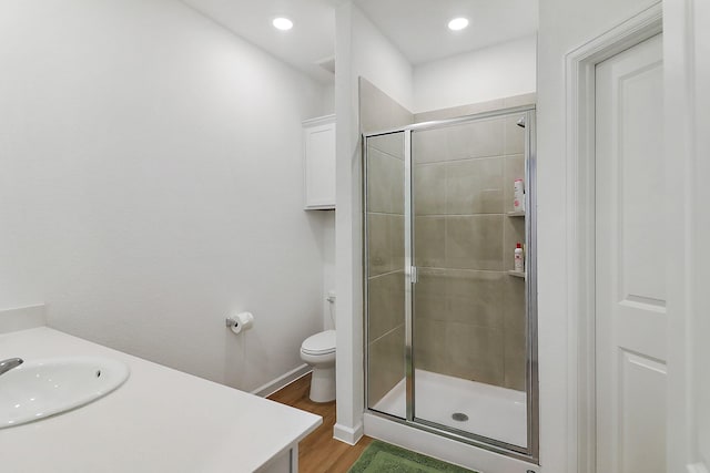 bathroom featuring vanity, wood finished floors, baseboards, a stall shower, and toilet