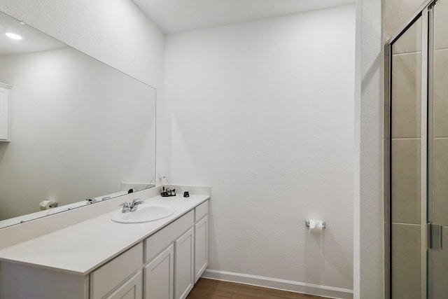 full bathroom with vanity, wood finished floors, baseboards, and a stall shower