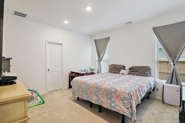 bedroom featuring visible vents, light colored carpet, and multiple windows