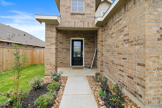 entrance to property featuring brick siding and fence