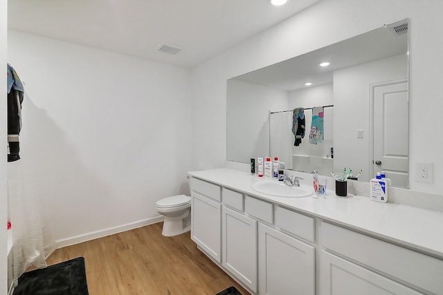 full bath with visible vents, toilet, vanity, and wood finished floors