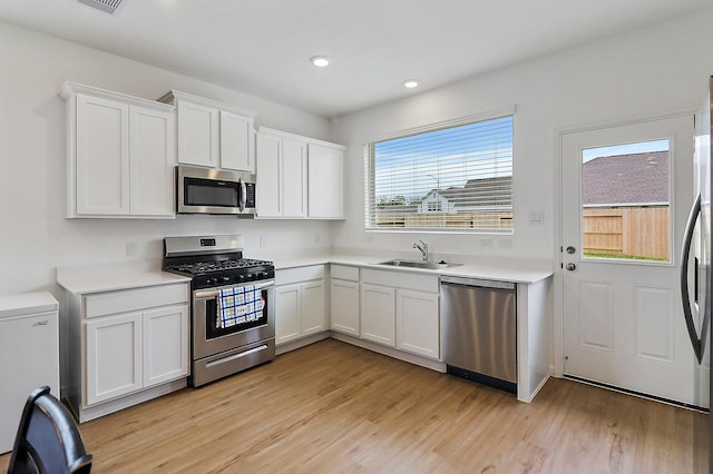 kitchen with light countertops, light wood finished floors, appliances with stainless steel finishes, and a sink