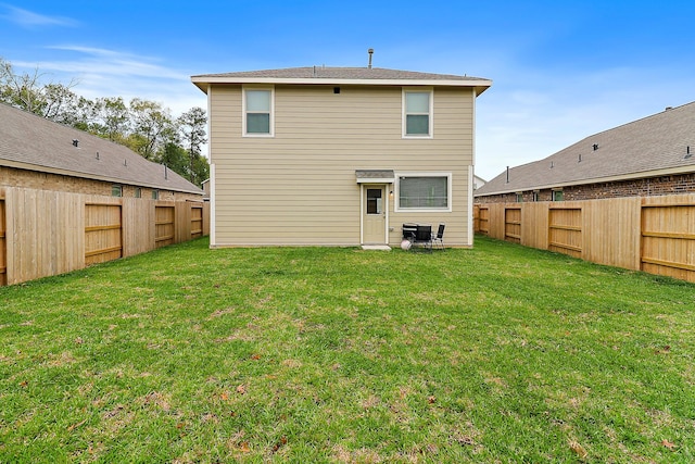 rear view of property featuring a lawn and a fenced backyard