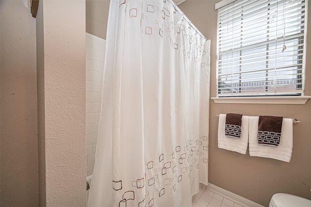 bathroom featuring tile patterned flooring, toilet, shower / tub combo, and baseboards