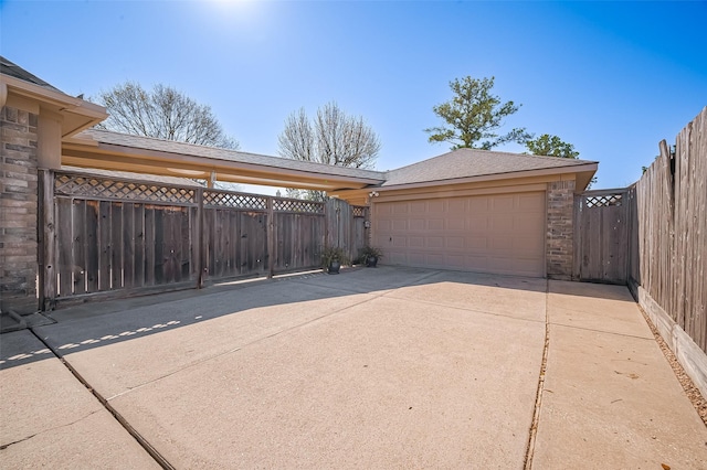 garage featuring concrete driveway and fence