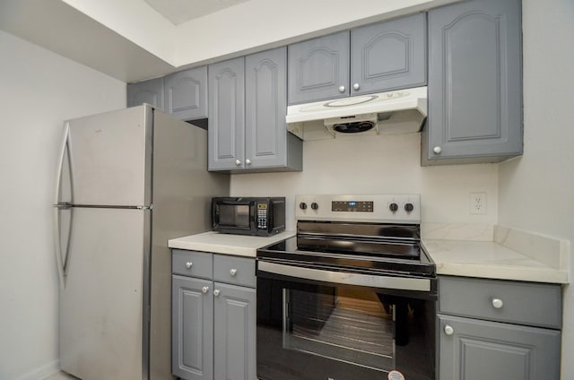 kitchen featuring gray cabinetry, black microwave, under cabinet range hood, stainless steel electric stove, and freestanding refrigerator