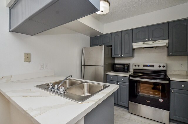 kitchen featuring under cabinet range hood, gray cabinets, a peninsula, stainless steel appliances, and a sink