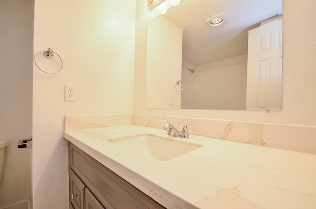 bathroom featuring toilet, a textured ceiling, and vanity