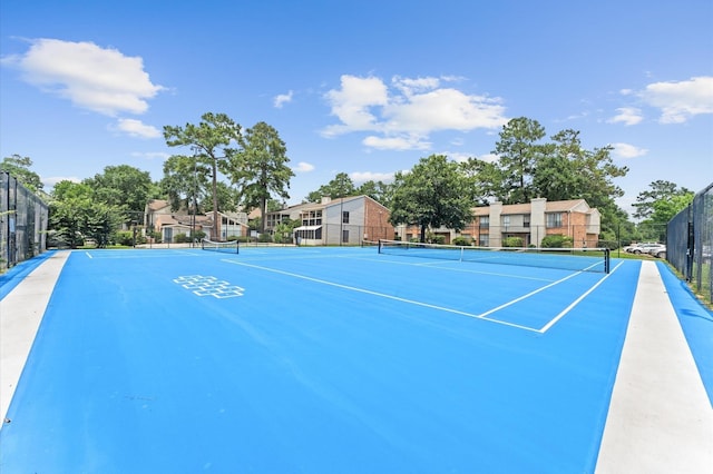 view of tennis court with a residential view and fence