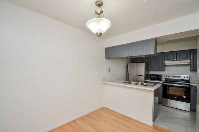 kitchen featuring a sink, appliances with stainless steel finishes, a peninsula, and light countertops