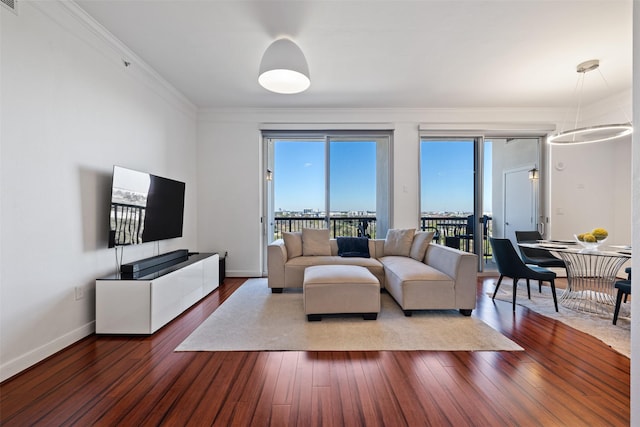 living area with dark wood-type flooring, crown molding, and baseboards