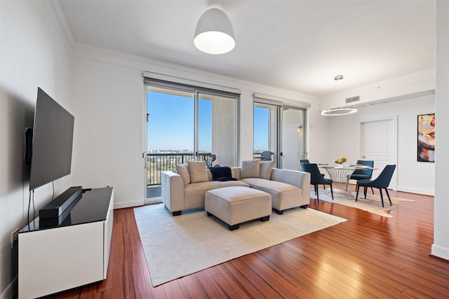 living room featuring visible vents, baseboards, ornamental molding, and hardwood / wood-style flooring