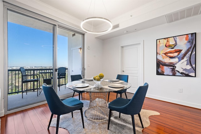 dining room with visible vents, baseboards, wood finished floors, and crown molding