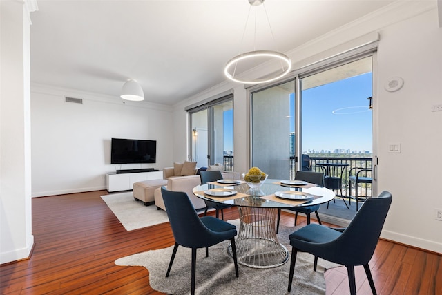 dining area with hardwood / wood-style floors, baseboards, visible vents, and ornamental molding