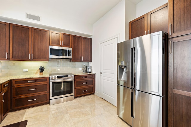 kitchen with light stone counters, stainless steel appliances, tasteful backsplash, and visible vents