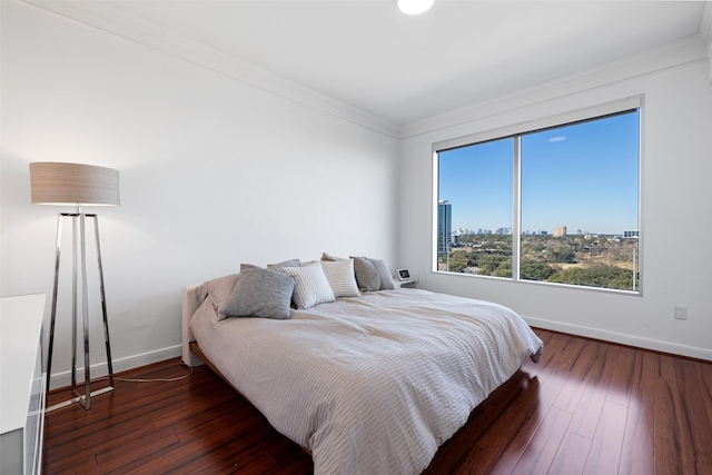 bedroom featuring a view of city, crown molding, baseboards, and hardwood / wood-style flooring