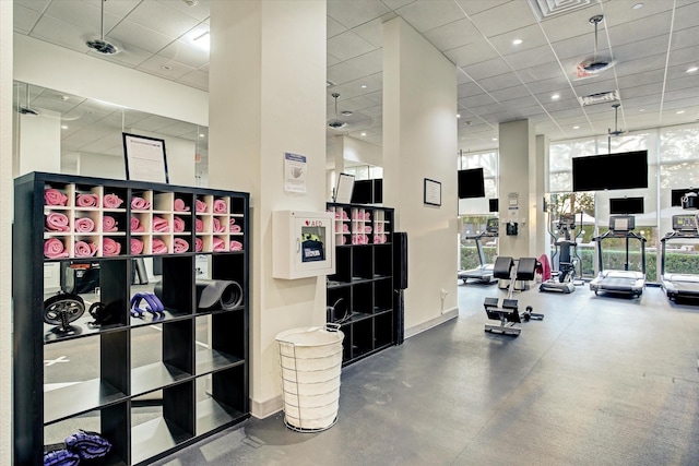 gym with a wall of windows, a drop ceiling, baseboards, and visible vents