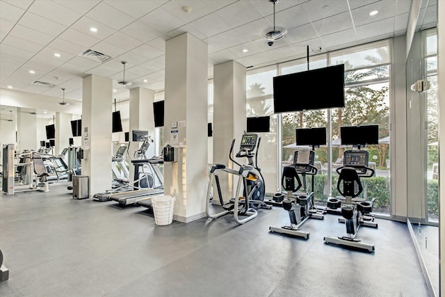 workout area featuring a wealth of natural light, visible vents, a drop ceiling, and expansive windows