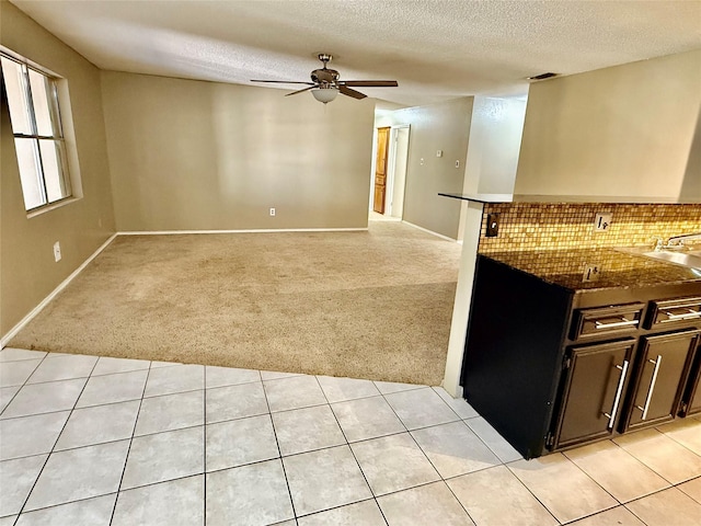 kitchen featuring light tile patterned floors, a ceiling fan, decorative backsplash, a textured ceiling, and light colored carpet