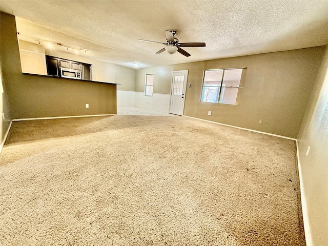 unfurnished room featuring ceiling fan, carpet floors, and a textured ceiling