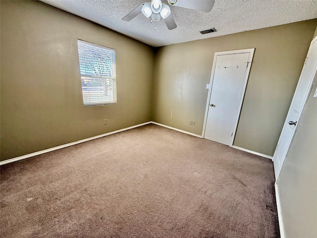 empty room featuring visible vents, baseboards, carpet floors, a textured ceiling, and a ceiling fan