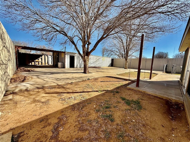 view of yard featuring a patio area, an outbuilding, and fence